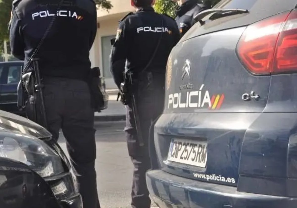 Dos agentes de la Policía Nacional con un coche patrulla