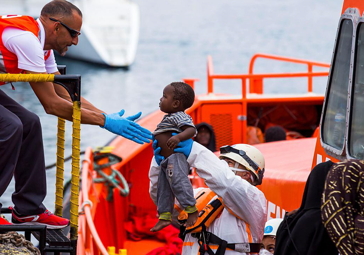 Personal de Cruz Roja ayuda al desembarco de un niño de unos meses en Canarias