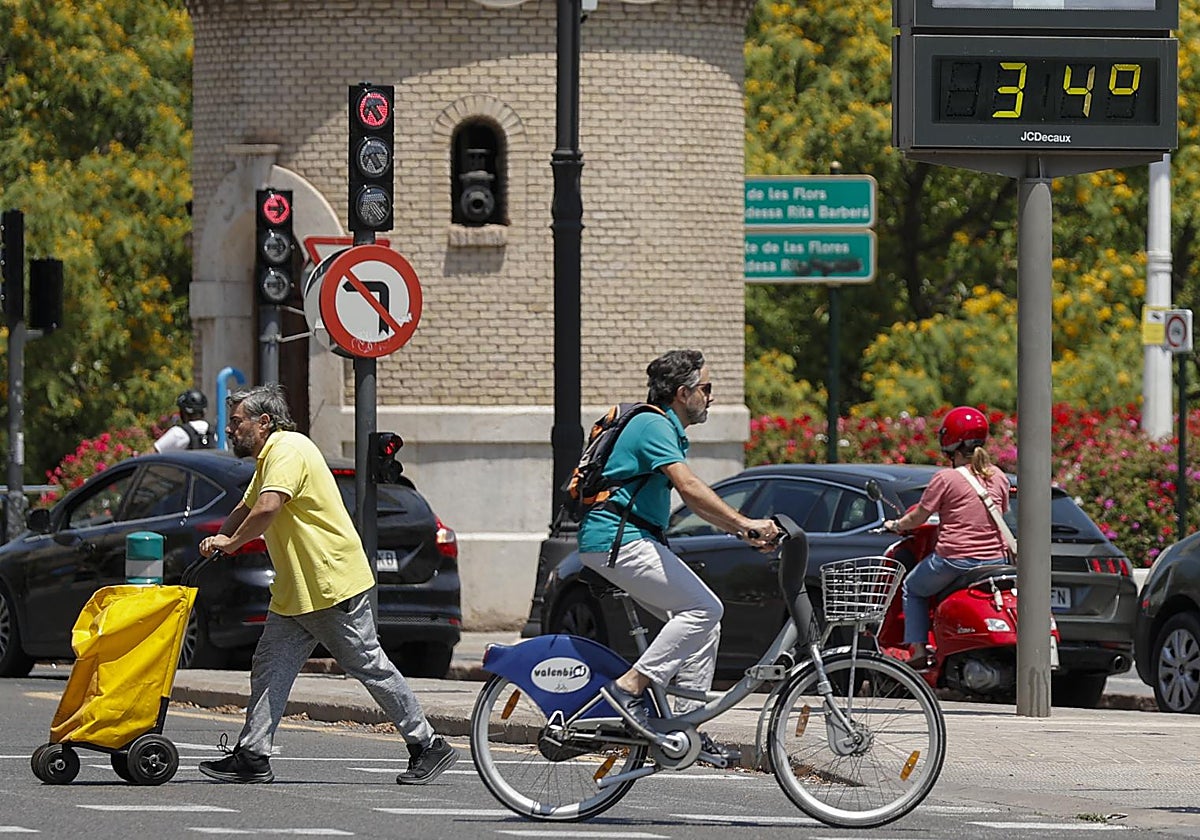 Varias personas pasan junto a un termómetro que marca los 34 grados centígrados