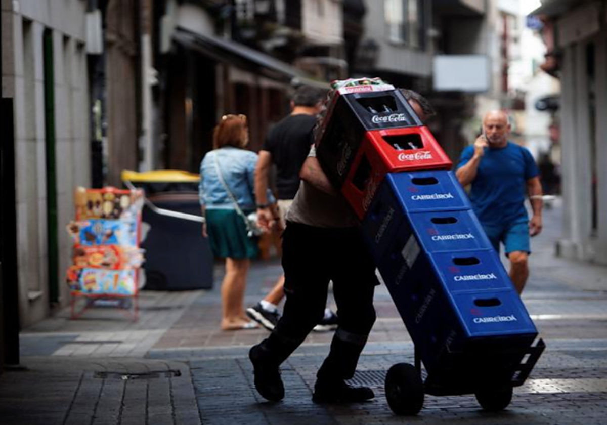Un repartidor carga con cajas de bebidas en foto de archivo.