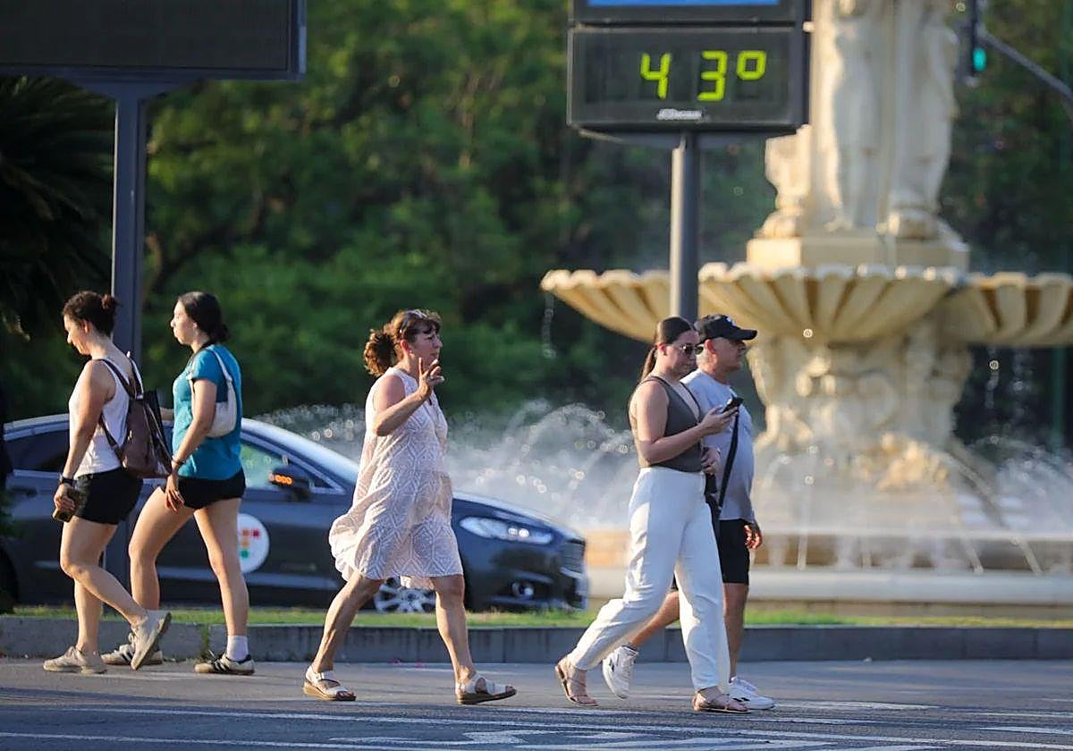 Varias personas caminan ante un termómetro que indica 43 grados