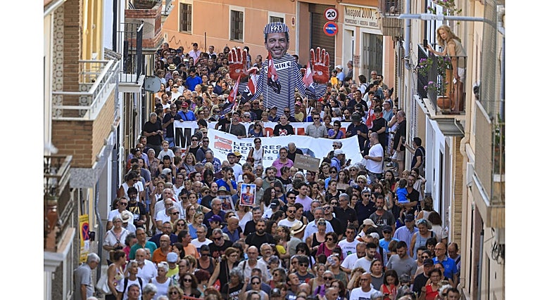 Paso de los manifestantes por una calle del municipio valenciano, con un estandarte del presidente de la Generalitat