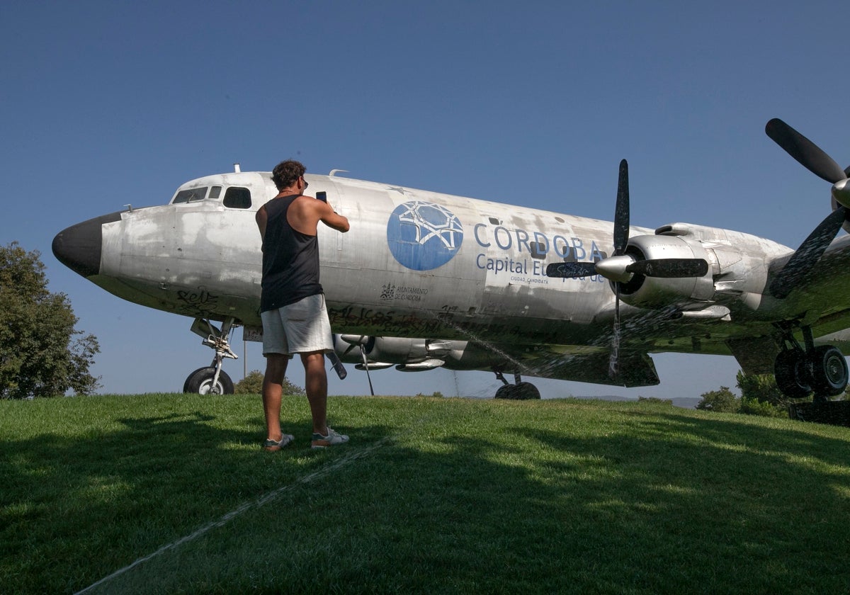 Un turista fotografía el avión cultural sobre la pequeña loma del Balcón del Guadalquivir