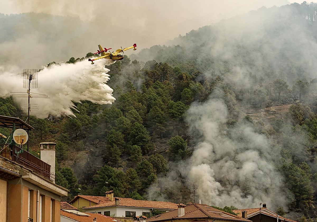 Un avión anfibio descarga cerca de las casas para intentar sofocar el incendio en el abulense Valle del Tiétar