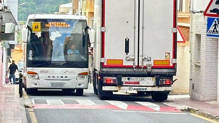 Dos vehículos pesados se cruzan casi rozándose por la estrechez de la calle en el casco urbano