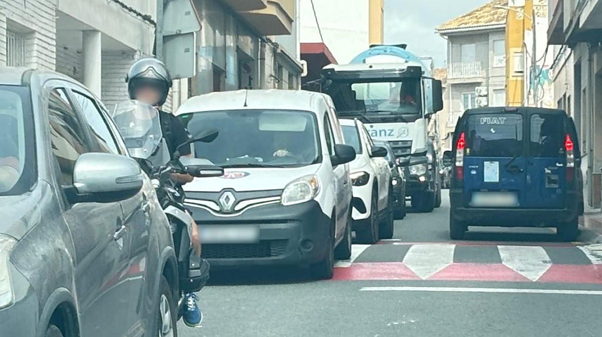 Atasco de tráfico con coches pasando casi sin espacio frente a un camión por el centro de Poble de Benitatxell, en una imagen difundida por el Ayuntamiento