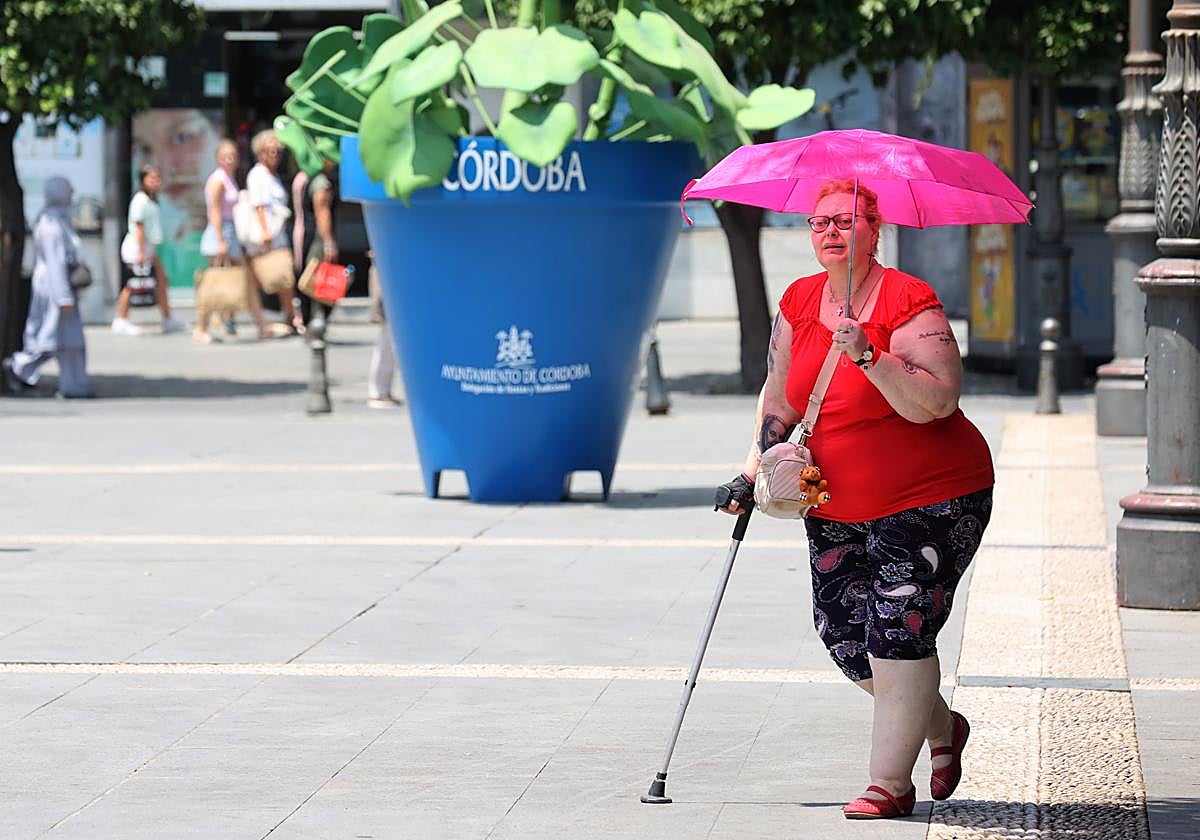 Una mujer se protege de las altas temperaturas con un paraguas en el Centro de Córdoba