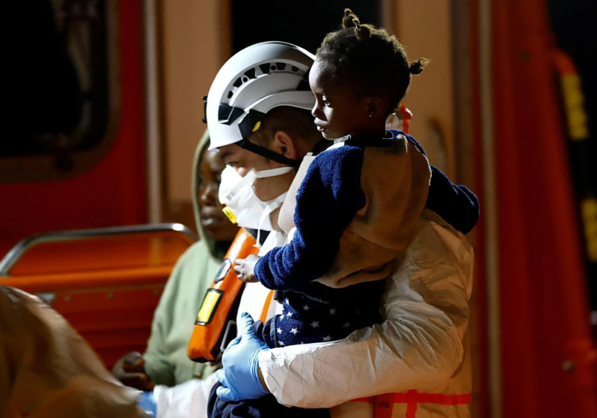 Un rescatador lleva en brazos a una niña rescatada de un cayuco cerca de Gran Canaria