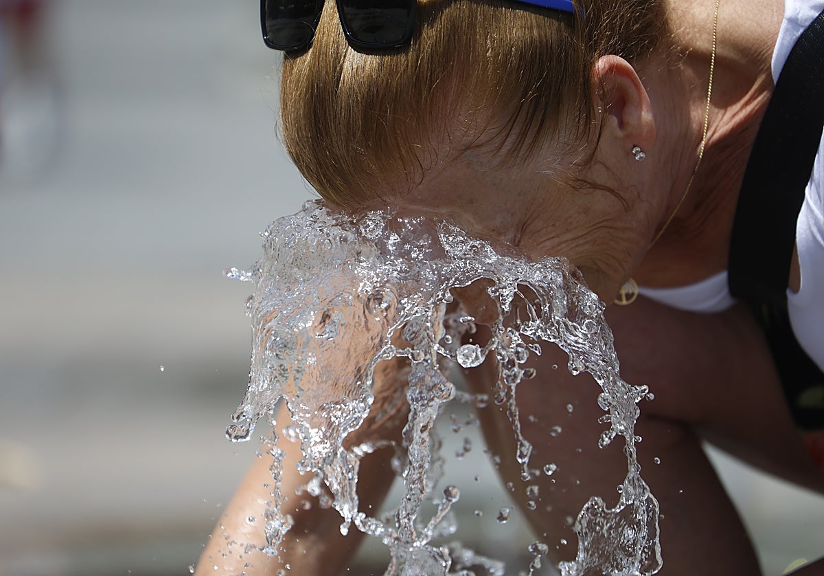 Una señora se refresca en una fuente de Córdoba