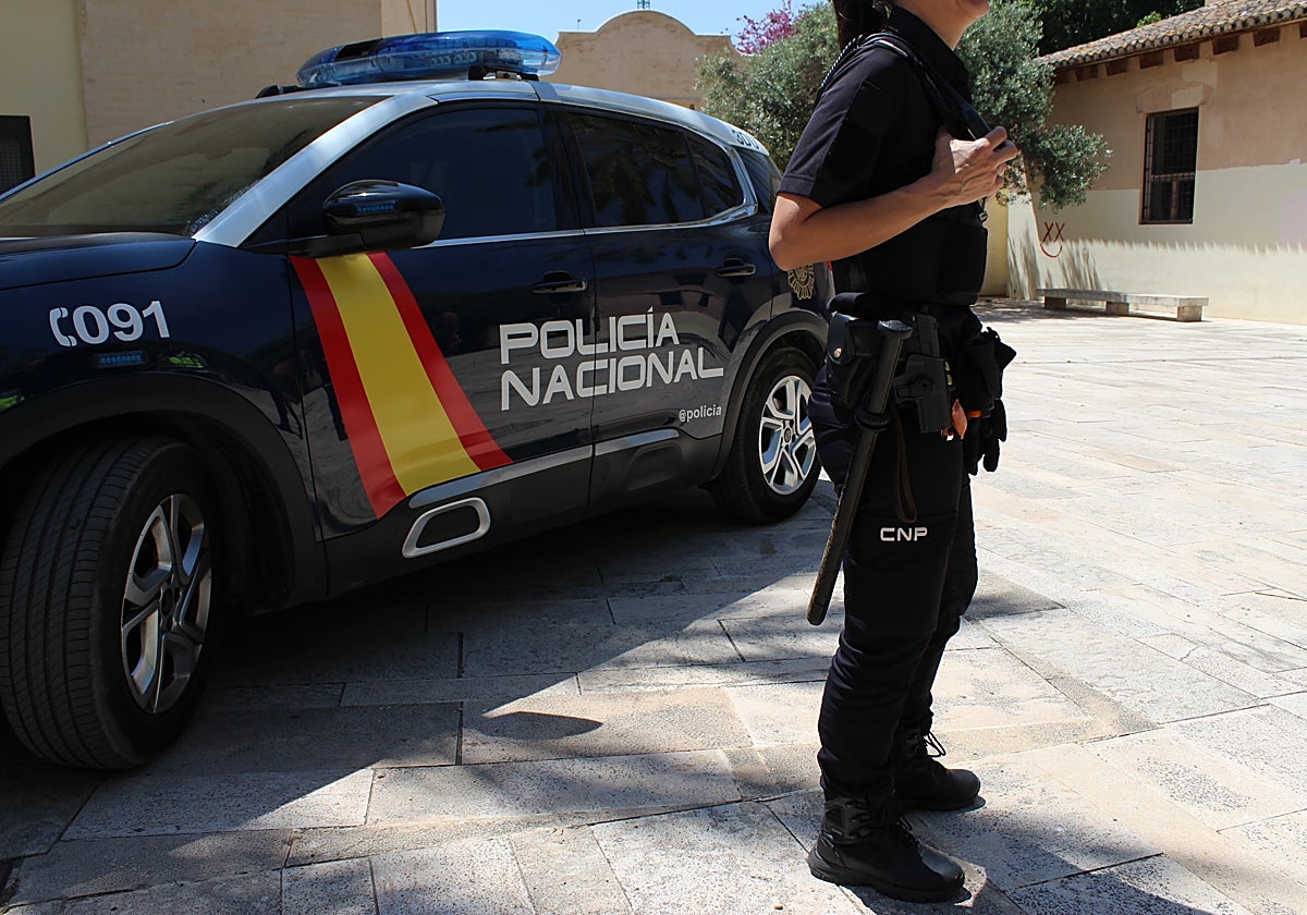 Una agente de la Policía Nacional de Valencia junto a un coche patrulla