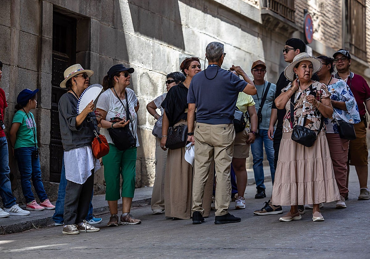 Un grupo de turistas se protege del intenso calor que soporta Toledo estos días con gorros, viseras y abanicos