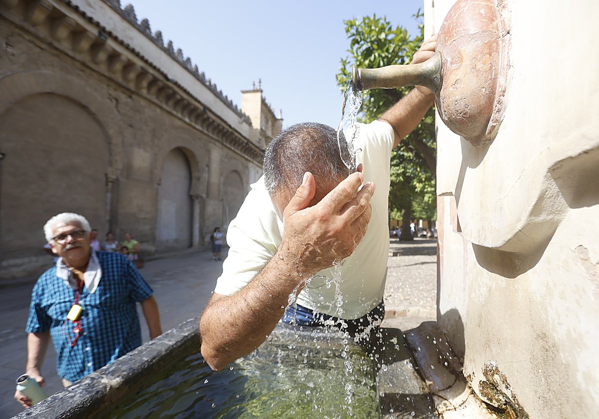 Un hombre se remoja en el Patio de los Naranjos para evadir el calor