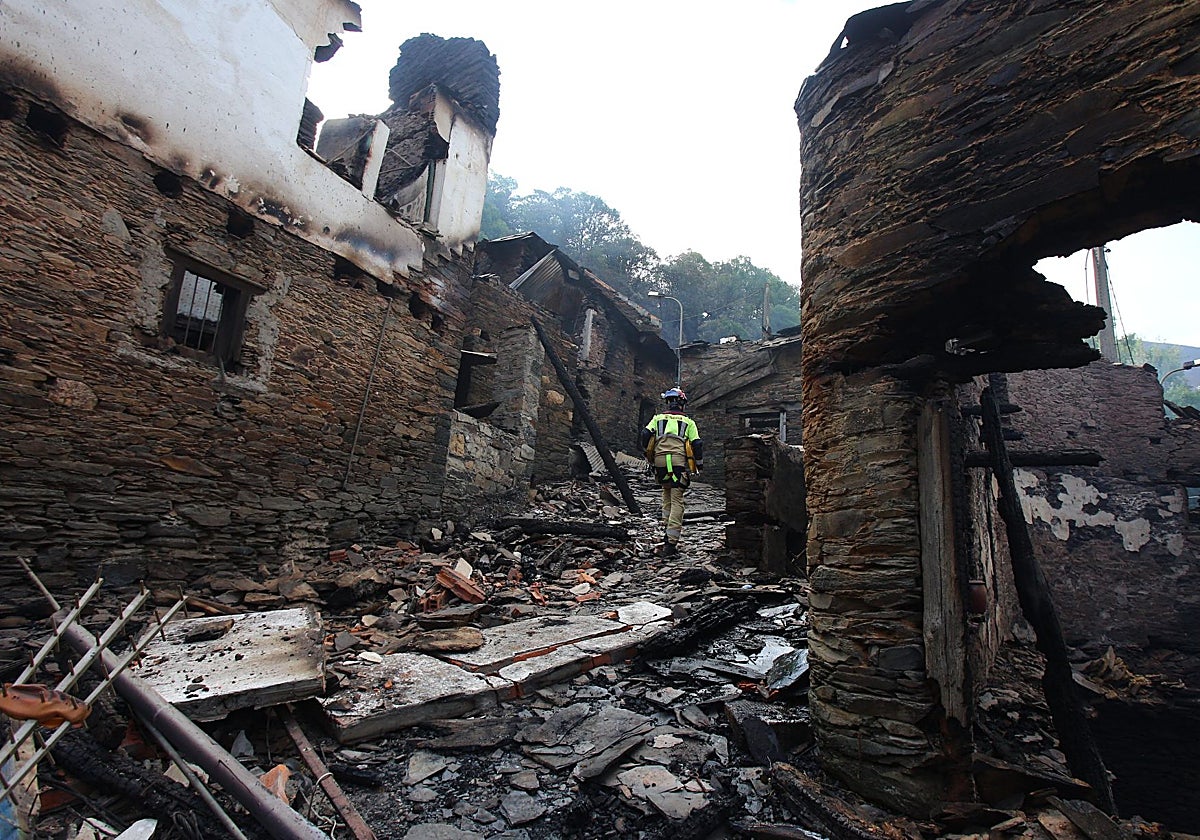Un bombero en una de las casas arrasadas por el fuego en Lusio (León)