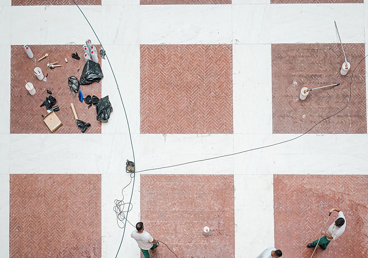 Varios operarios rehabilitando el suelo de la Real Casa de Correos