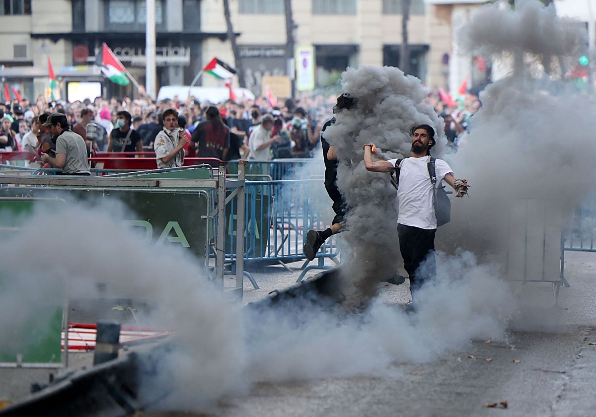 Un manifestante lanza bombas de gas contra la Policía, durante una carga ayer en la etapa final de la Vuelta a España