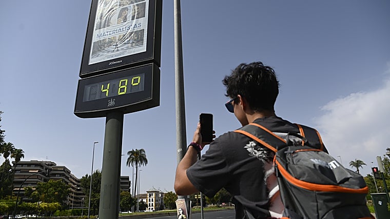 Un visitante fotografía un hito de temperatura en la avenida Vallellano a 48 grados al sol