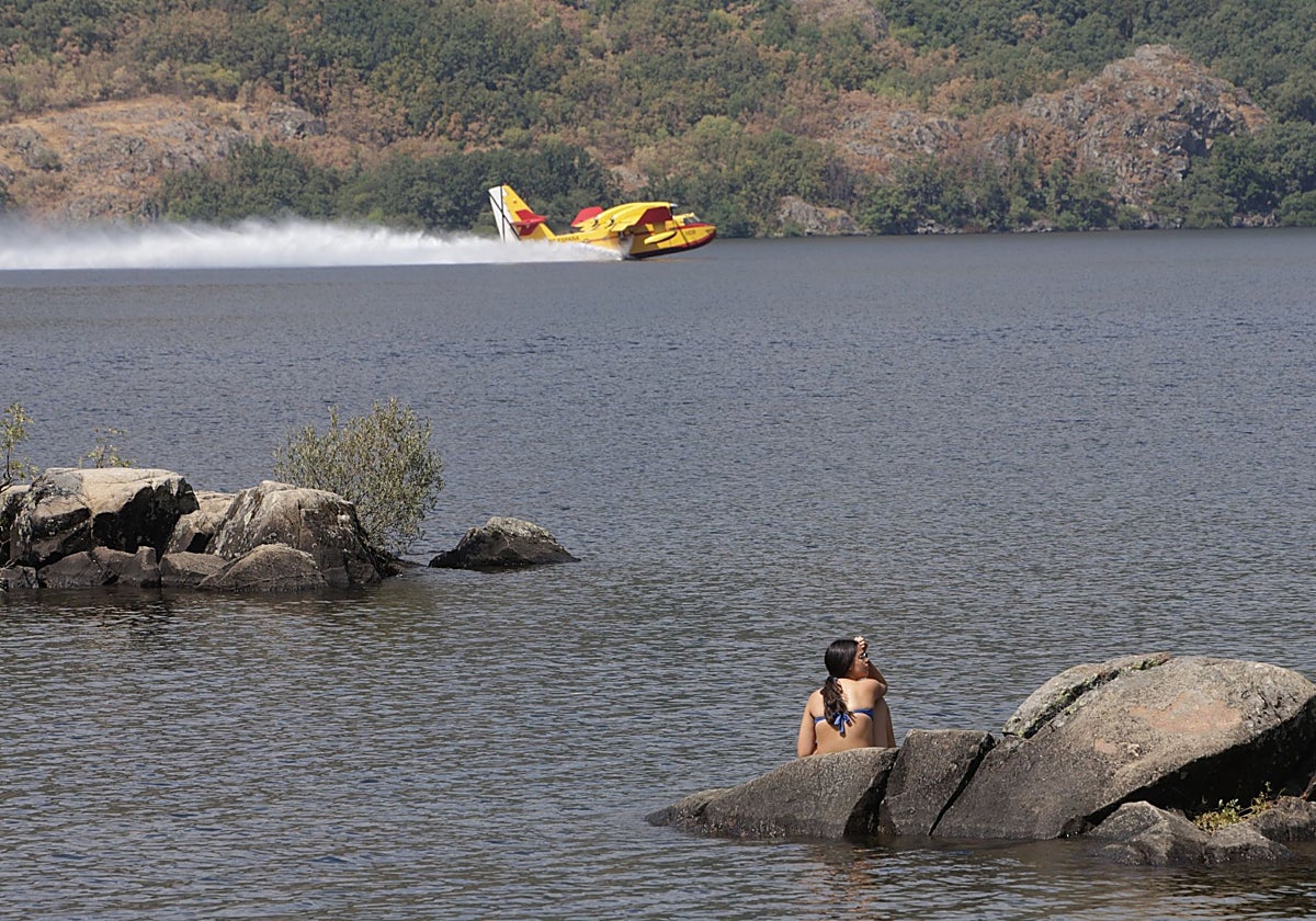 Un bañista en el Lago de Sanabria el pasado agosto mientras un hidroavión recoge agua