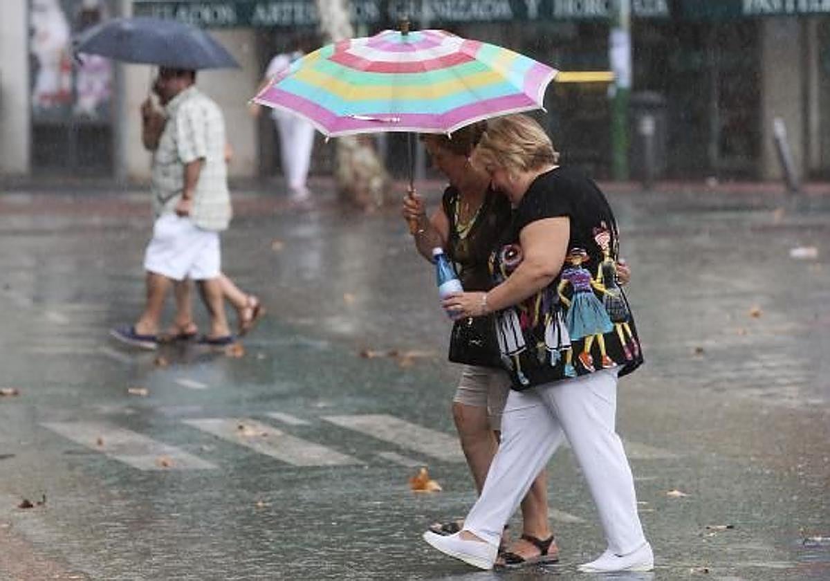 Dos señoras se resguardan de la lluvia con su paraguas