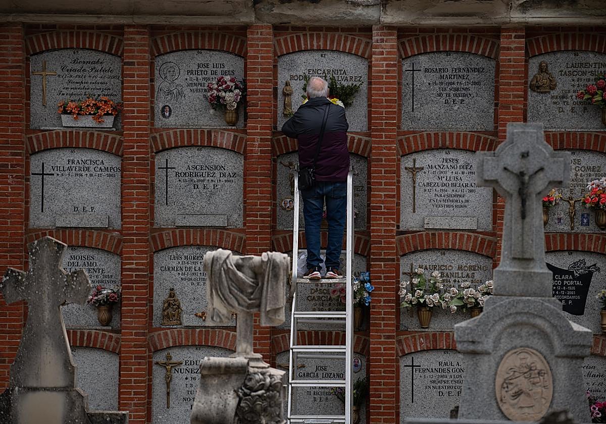 Un hombre pone flores en un nicho, ayer, en el cementerio de La Almudena