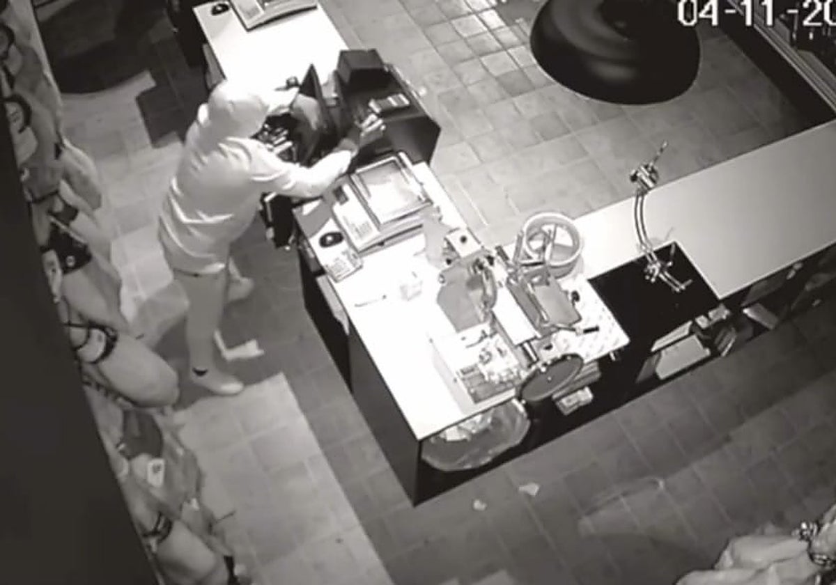 Uno de los ladrones haciéndose con la caja registradora en el atraco