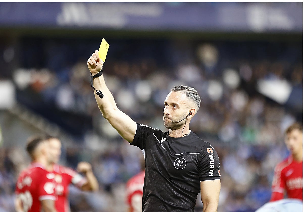 Orellana Cid muestra una amarilla en el partido entre el Córdoba CF y el Málaga
