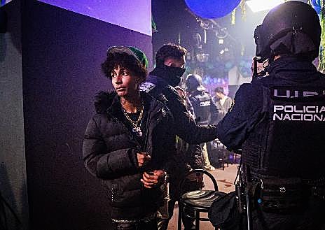 Imagem Secundária 1. Após identificá-los, os agentes revistam todos os presentes. Vito, do departamento canino, está em busca de drogas.