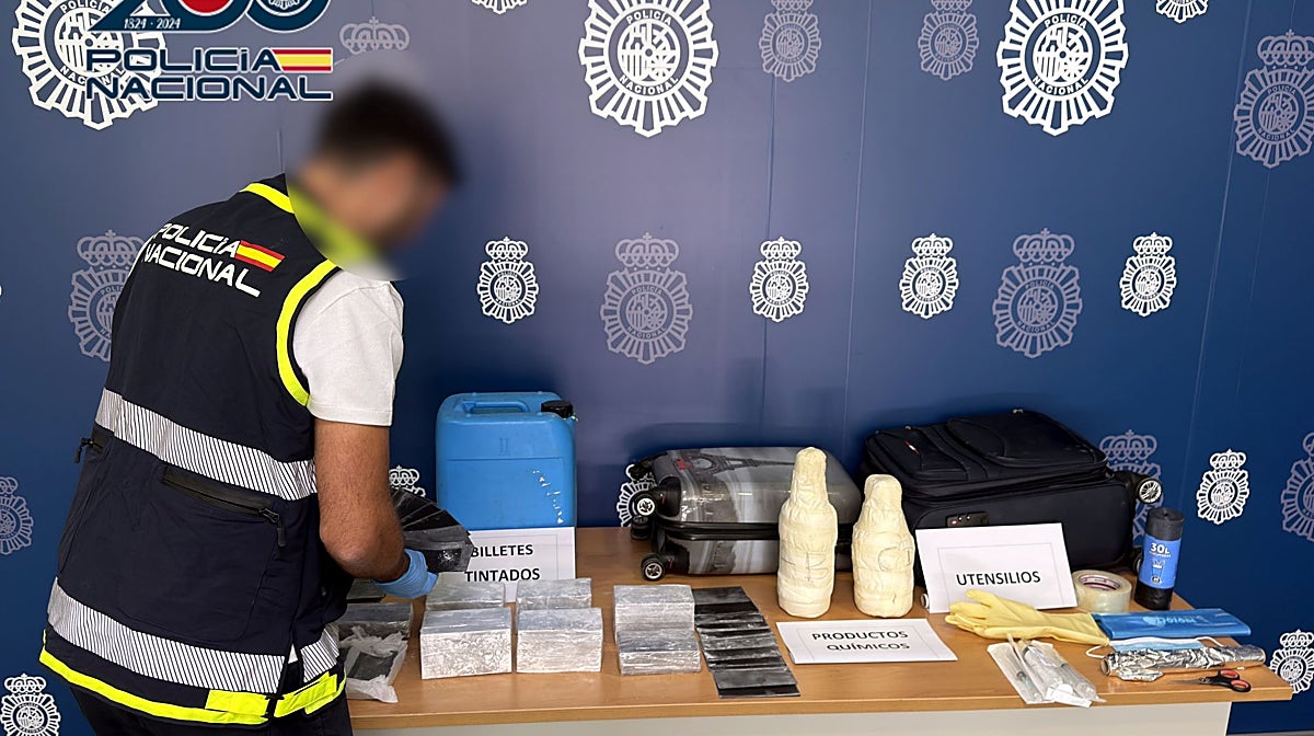 Imagen de un agente policial con el material requisado en Alicante para estafas con billetes