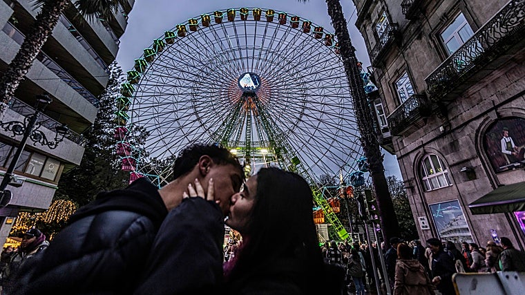 Two young tourists kiss next to the Ferris wheel, the epicenter of Christmas in Vigo