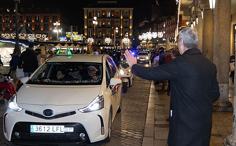 Main image - Above these lines, a passerby welcomes the caravan crossing the Plaza Mayor of Valladolid. Below, participants in this initiative in Salamanca take a photo and taxis cross one of the illuminated streets of Valladolid