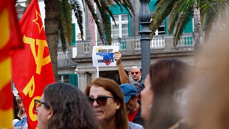 Un manifestante muestra un cartel con el mensaje 'Hands off Venezuela'
