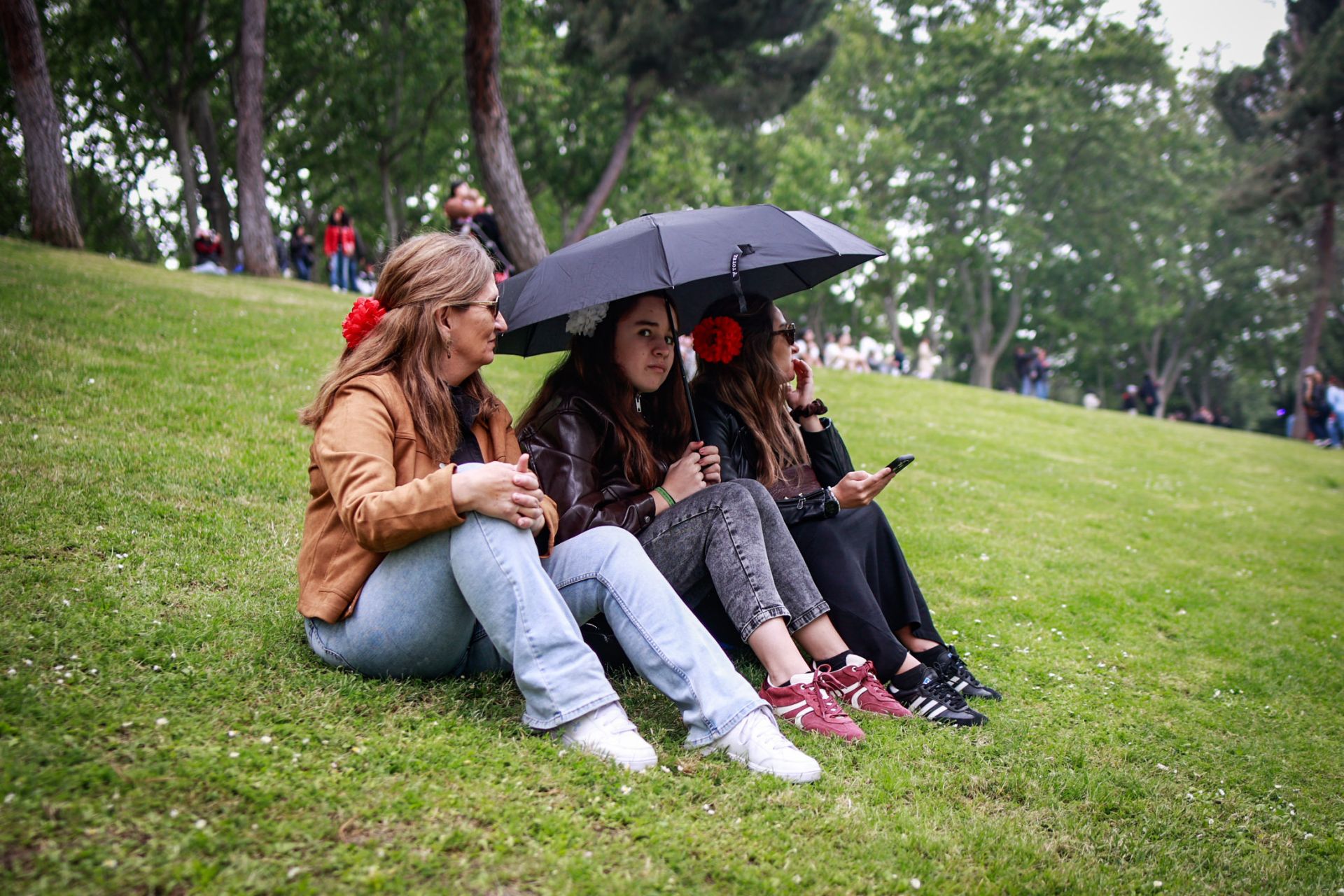Varias personas se resguardan de la lluvia en la Pradera de San Isidro
