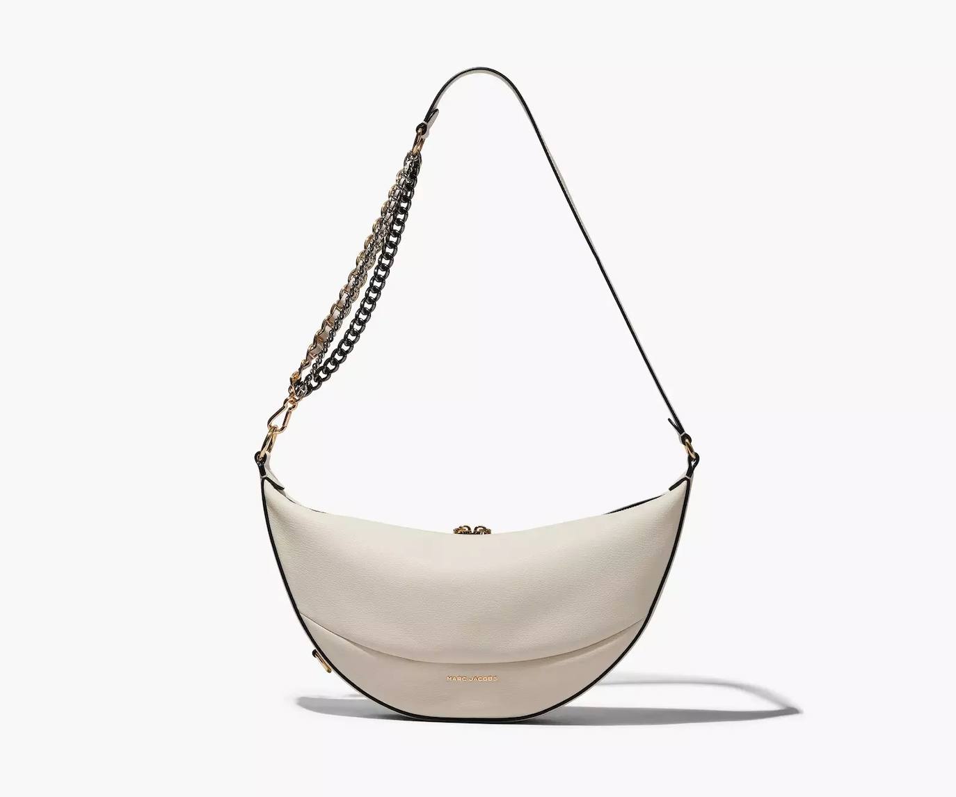 Modelo The Eclipse Shoulder Bag en forma de luna creciente de Marc Jacobs. Un accesorio perfecto para eventos de noche en color ivory, tiene un precio rebajado en 475€.