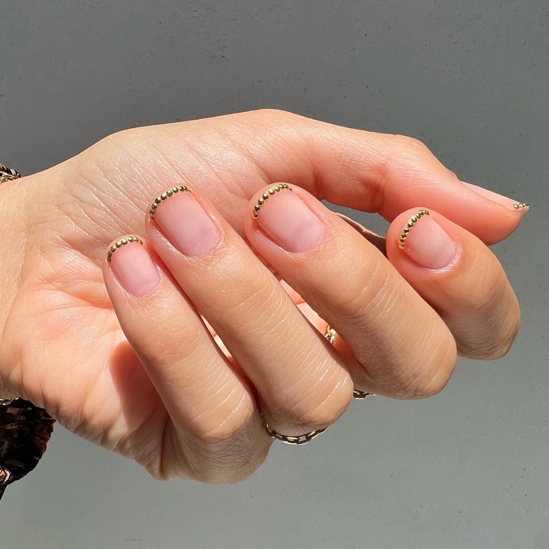 Manicura francesa joya en dorado. Otra forma de lucir la manicura francesa este verano de forma elegante es decorando la parte superior con un discreto 'nail art' dorado. También se puede elegir una fina línea dorada o plateada.