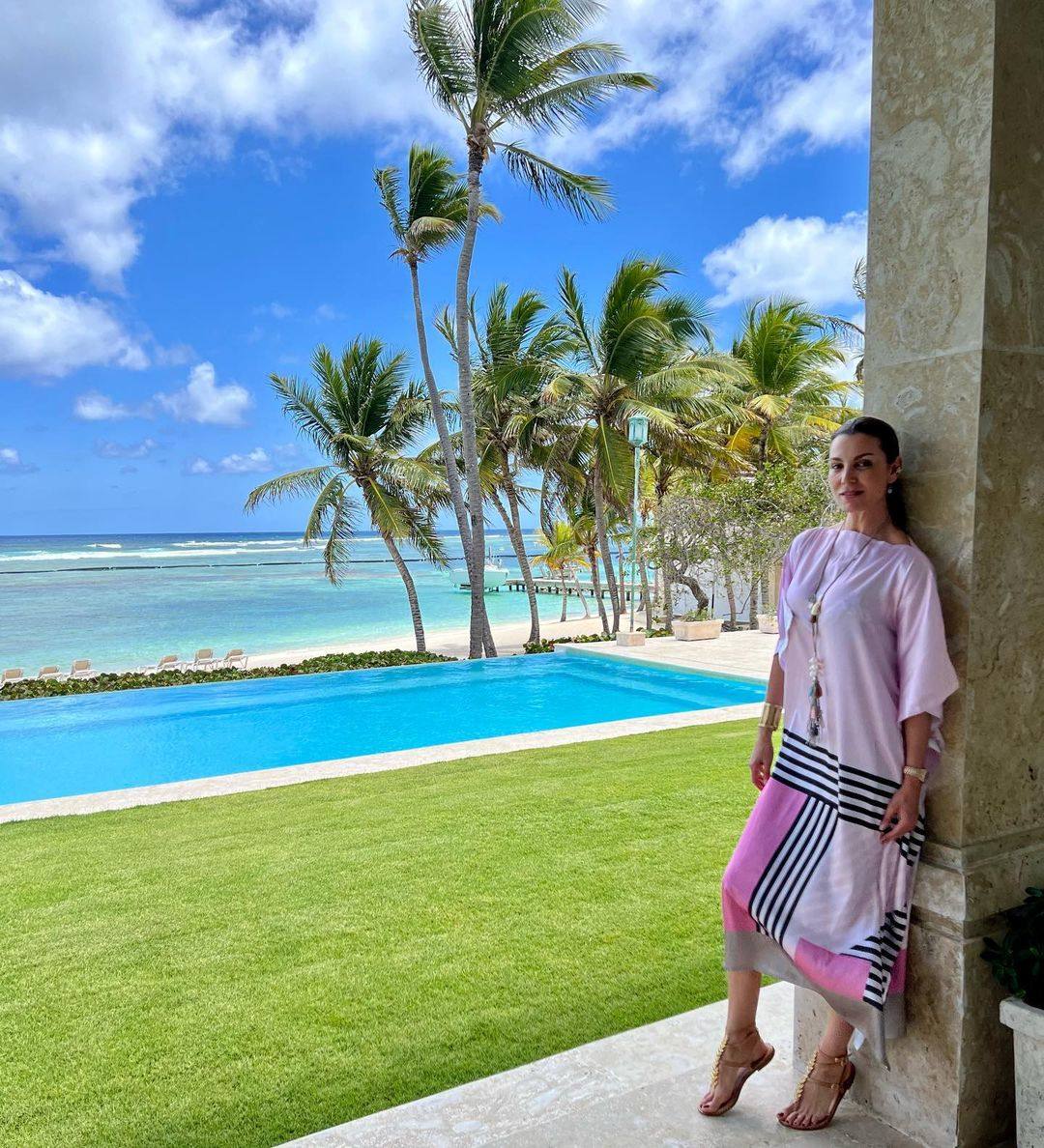 Mar Flores elige para sus días de playa un caftán  menos colorido pero muy sofisticado en tonos rosas y detalles en negro y beige que ella ha combinado con un colgante largo para convertir el modelo en algo más que una prenda 'beachwear' 