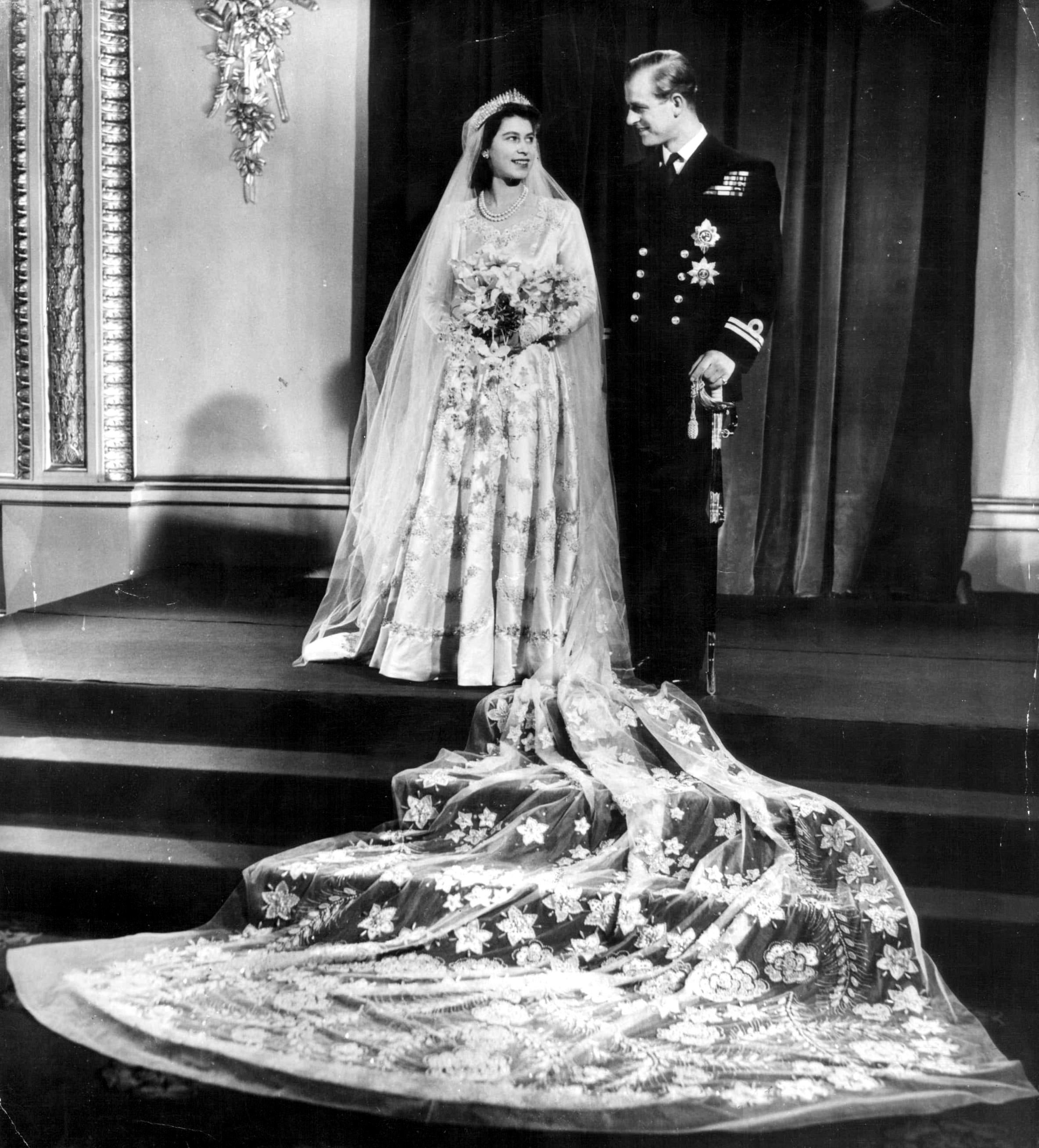 El 20 de noviembre de 1947, Isabel II y Felipe de Edimburgo se convertían en marido y mujer en la Abadía de Westminster, un día en el que sin duda el vestido de la novia era una las piezas clave. La Reina se decantó por un vestido de escote corazón y mangas ajustadas firmado y hecho a medida por Norman Hartnell para la ocasión. Para confeccionarlo fueron necesarias varias semanas y cientos de costureras. Entre los detalles más llamativos se encuentra las 10.000 perlas bordadas que llevaba el diseño, incrustaciones de cristal y lentejuelas. Según los rumores, el creador se habría inspirado en 'La primavera' de Botticelli para idearlo