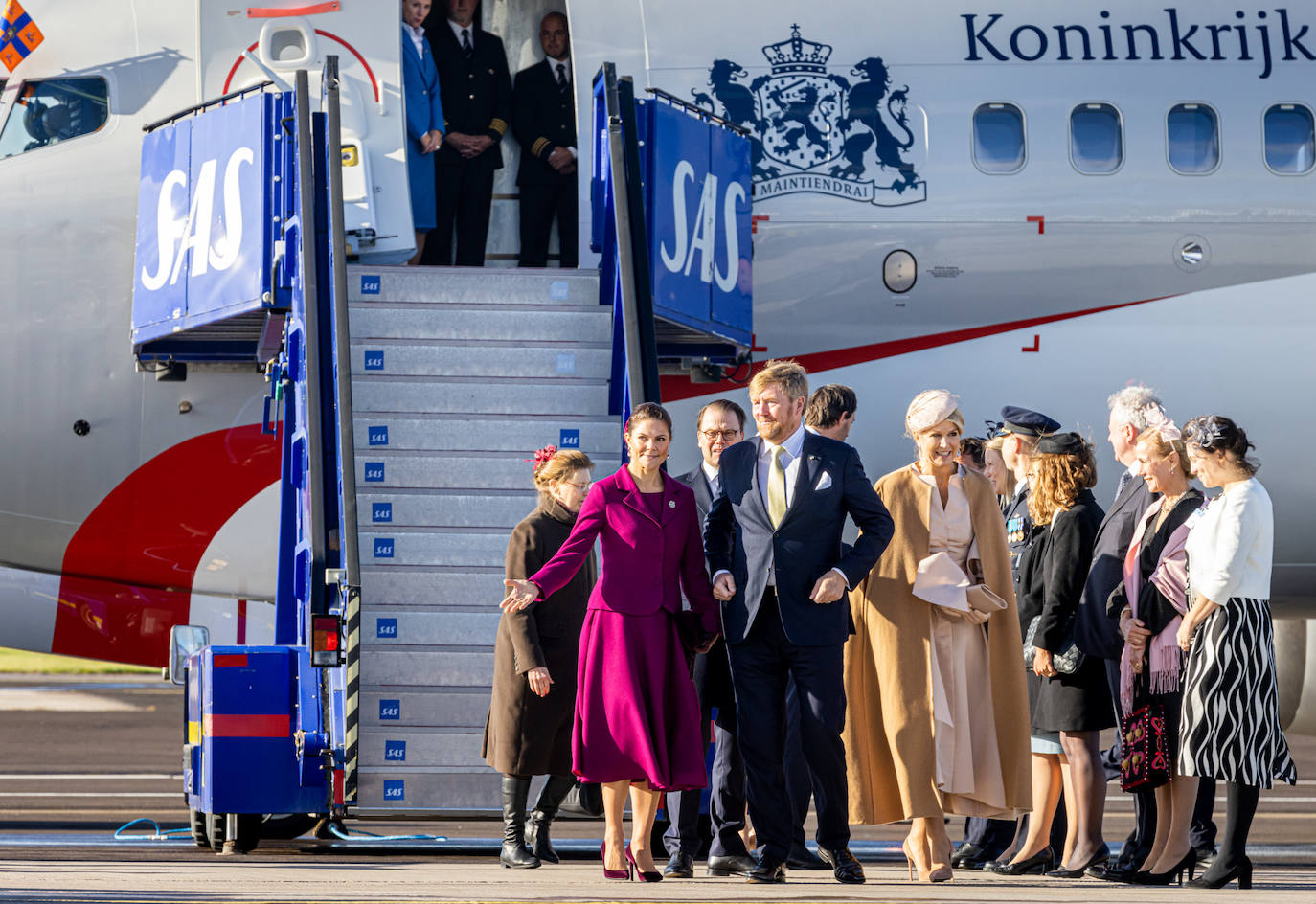 Los Reyes de Holanda llegaban a Estocolmo el martes 11 de octubre. En el aeropuerto les esperaba la princesa Victoria. Máxima de Holanda viajaba con un elegante vestido, que combinaba con un discreto tocado. Sobre los hombros, para hacer frente a las bajas temperaturas de la capital sueca, la argentina llevaba una capa de Valentino.