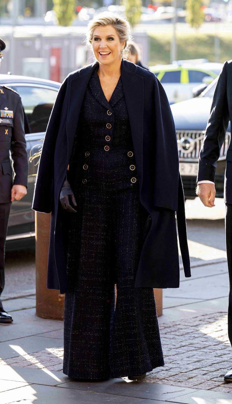 Por la tarde, para visitar el parque de la Ciencia de Estocolmo, la reina elegía otro 'outfit' más cómodo. Se trata de un conjunto de tweed en azul marino formado por unos pantalones anchos y chaqueta entallada con botones dorados. Lo completaba con un abrigo azul marino, junto a unos guantes de piel también en este color, bolso tipo cartera y unos botines de suela track.