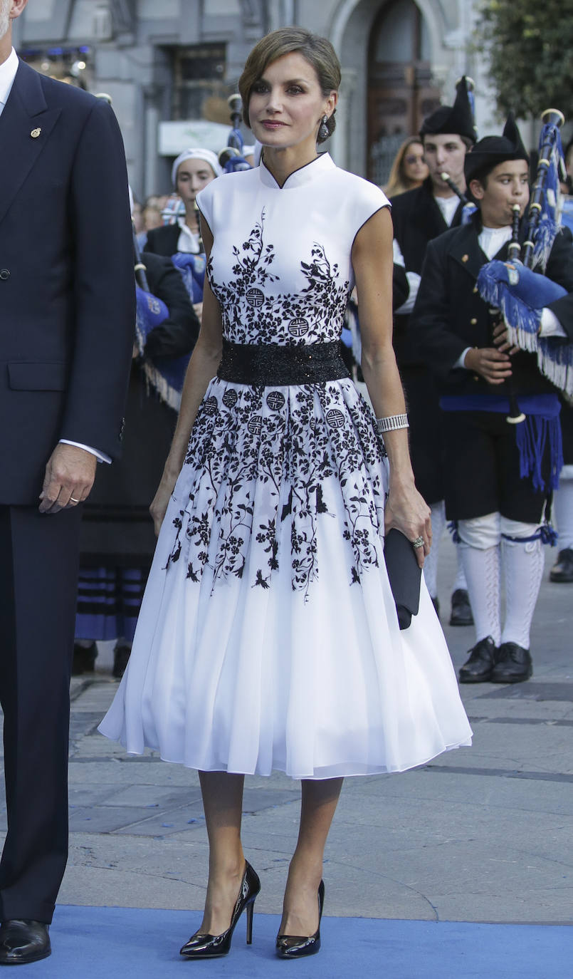 Para la ocasión, Letizia optó por un vestido blanco adornado con motivos florales de encaje en cristales de Swarovski negro, firmado por Felipe Varela. Para completar el look, la reina llevó stilettos de charol negros, clutch del mismo color, pendientes de diamantes de De Grisogono y pulsera de Cartier del joyero real.