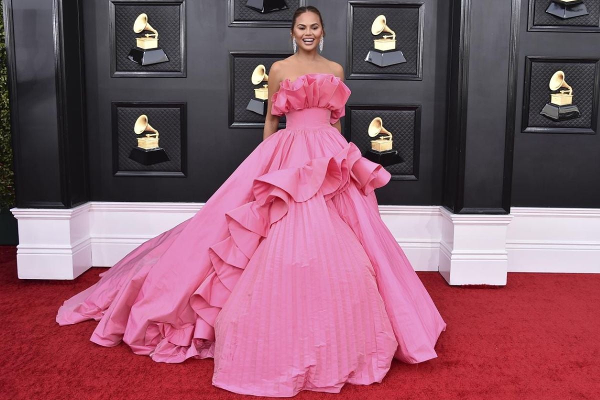 Chrissy Teigen en los Grammy 2022. La esposa de John Legend es todo un icono de estilo y en la última edición de los Grammy 2022 se consagró como una de las más llamativas y coloridas de la noche con un voluminoso vestido rosa con volantes XXL y escote palabra de honor con otro gran volante de Nicole + Felicia.