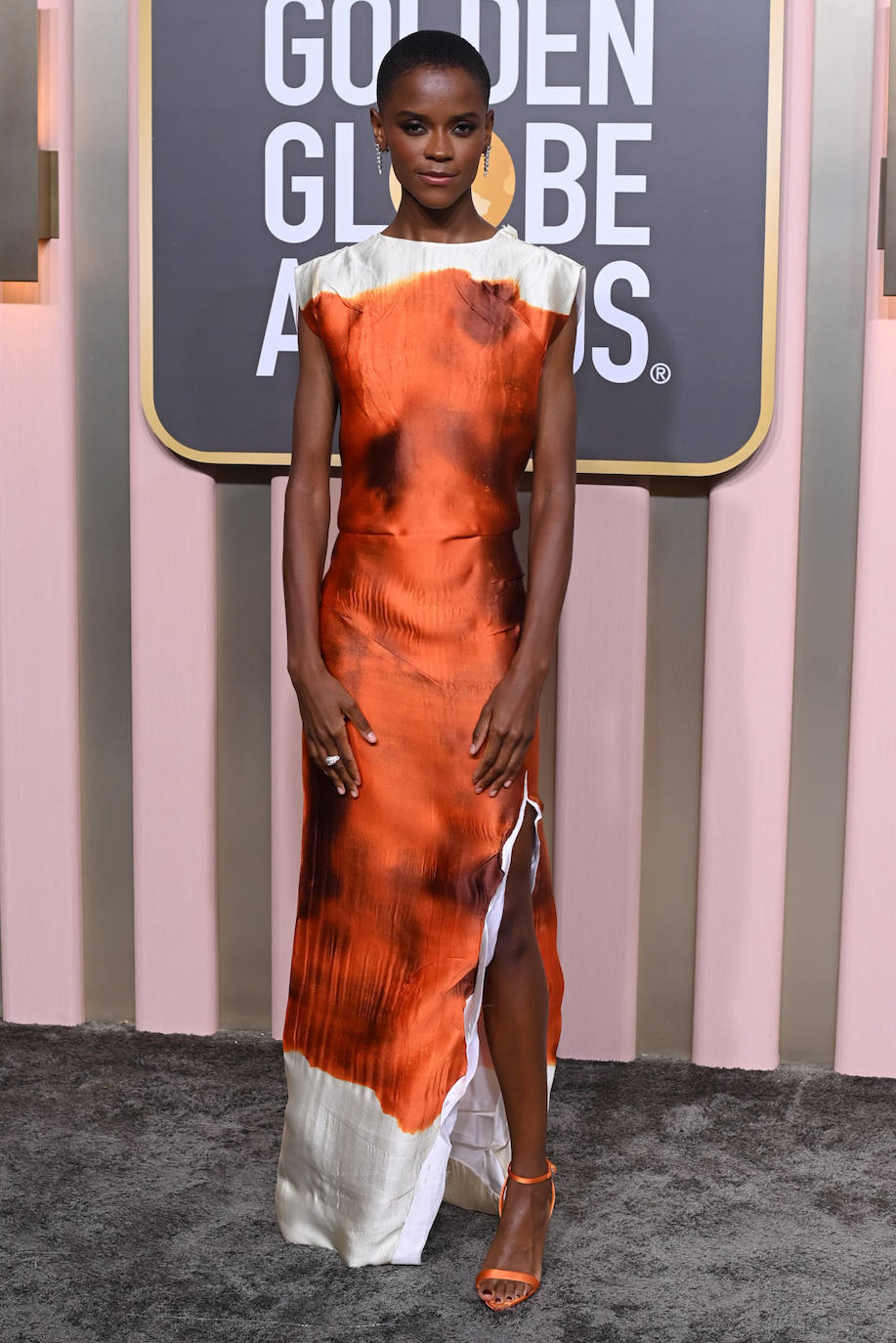 Letitia Wright con un original vestido naranja y blanco de Prada. Se trata de un diseño de la colección primavera-verano 2023 inspirado en el papel arrugado. 