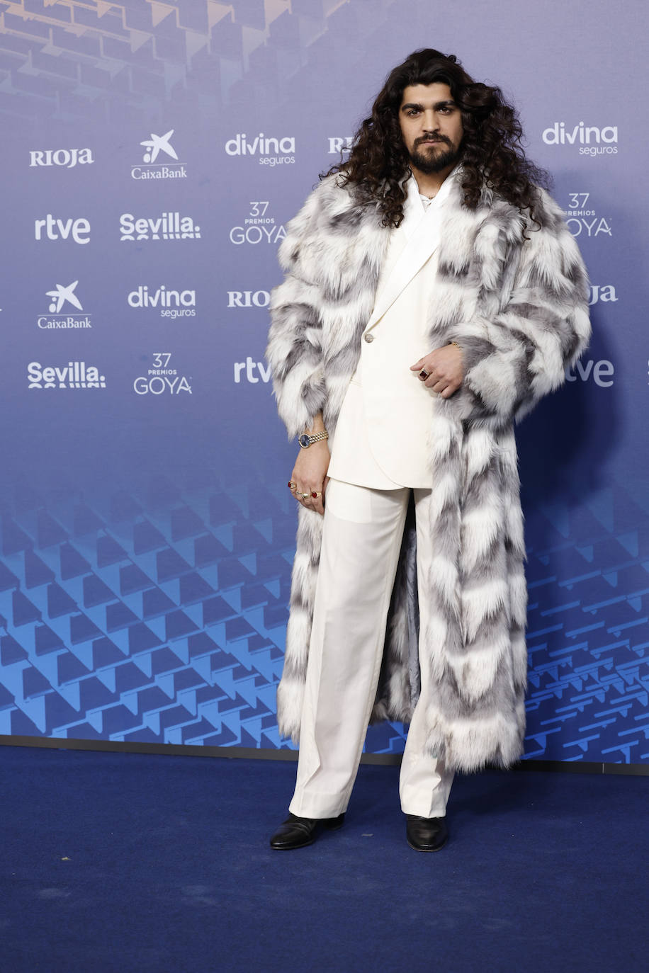 El cantaor Israel Fernández con traje blanco y abrigo de piel. 