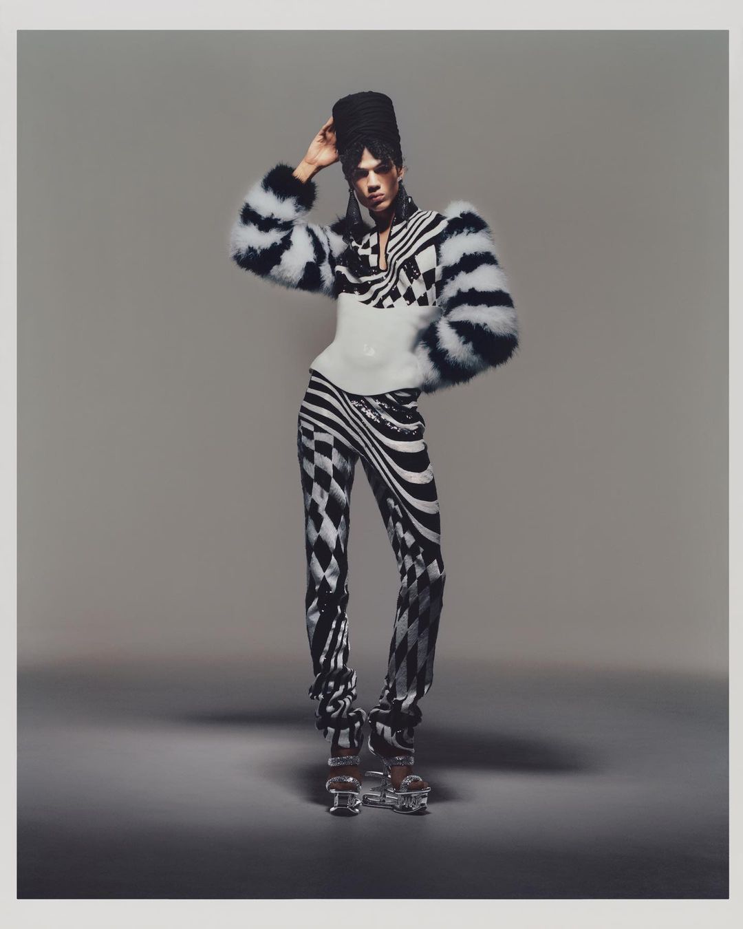 Conjunto gráfico bordado con lentejuelas y plumas, pendientes drapeados en malla metalizada y turbante negro.