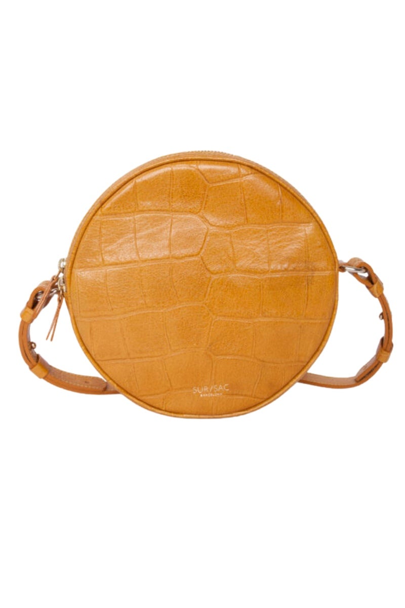 Bolso en forma redonda, modelo Matilda, de Sursac. Realizado en piel de vacuno con grabado de cocodrilo. Se cierra con una doble cremallera que rodea el bolso. Ideal para aquellas mamás que necesitan espacio de almacenaje sin tener que renunciar al estilo. Precio: 265€.