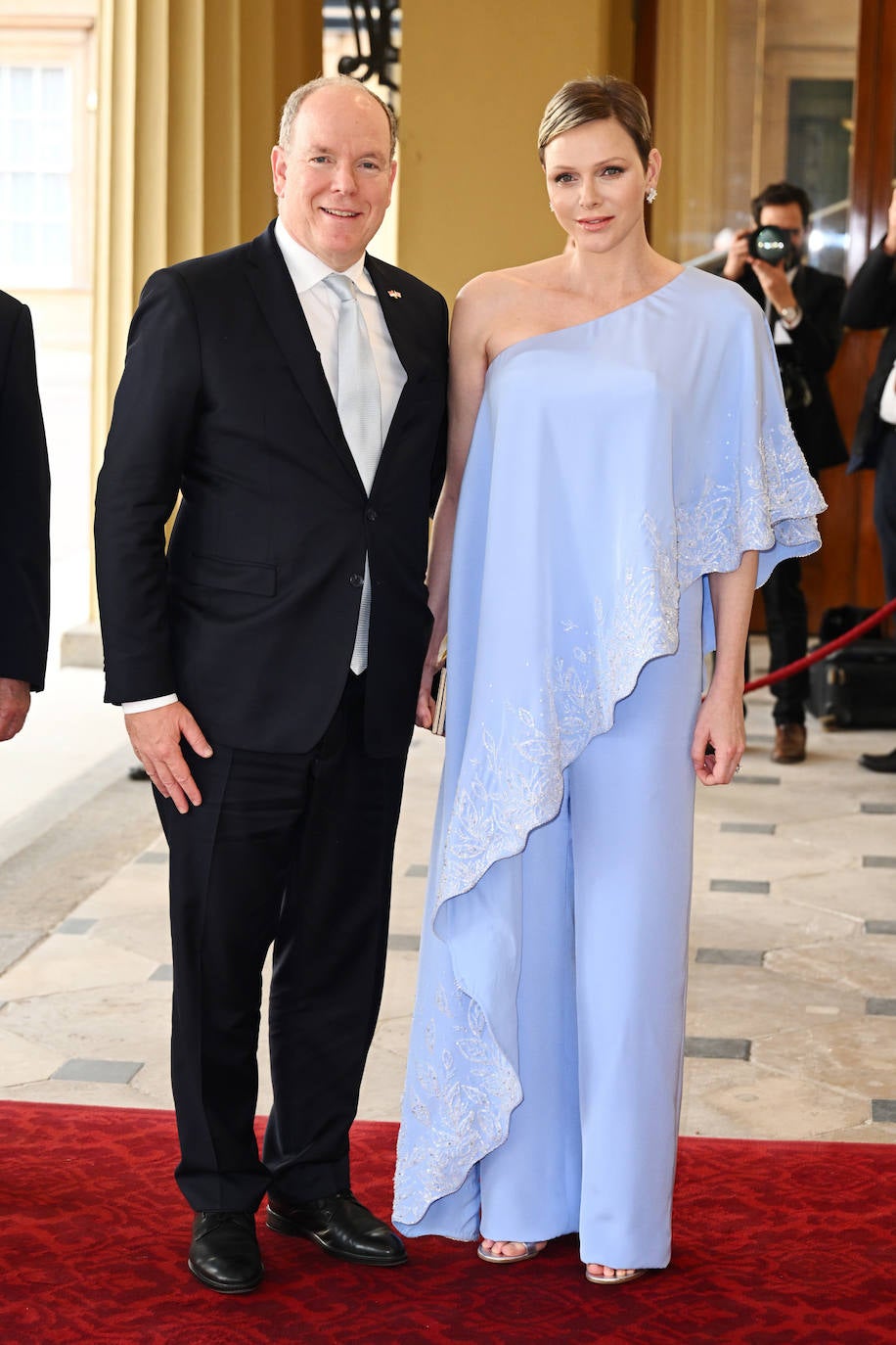 Charlene de Mónaco ha elegido un original estilismo en color azul celeste con bordado en blanco, formado por un pantalón amplio y un top asimétrico. Lo ha combinado con sandalias plateadas de Manolo Blahnik. 