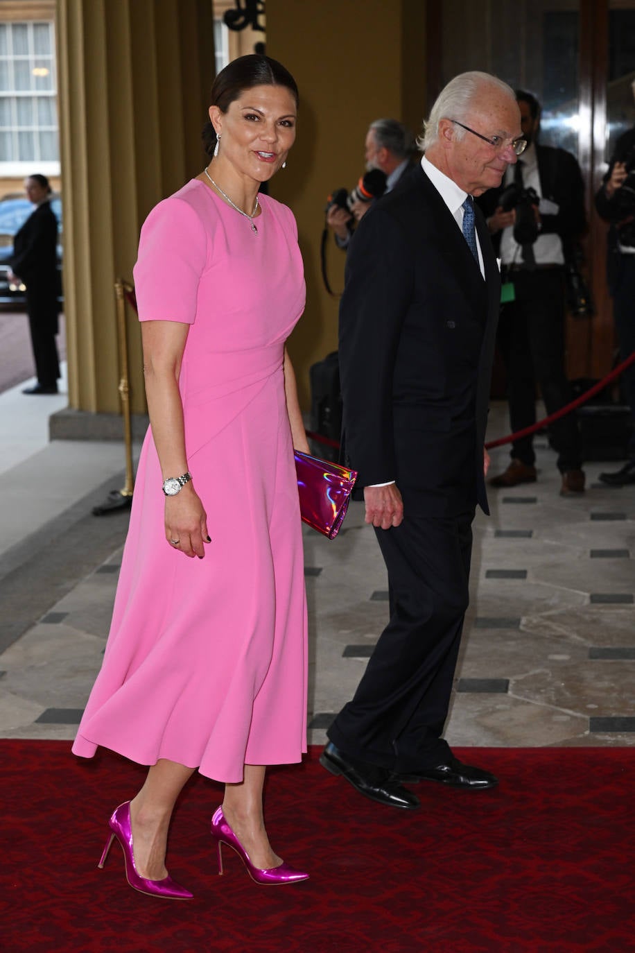 Victoria de Suecia se ha decantado por un sencillo vestido de corte midi en color rosa de la firma Roland Mouret que ha combinado con salones y bolso en tono fucsia metalizado. Los zapatos son de Louboutin y el bolso de Gianvito Rossi. La heredera, que ha acudido con su padre, el rey Gustavo, ha combinado su estilismo con un moño bajo y unos valiosos pendientes de la firma sueca Engelbert de oro y diamantes que están a la venta por más de 18.000 euros. 