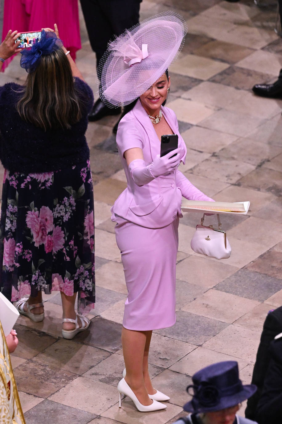 Katy Perry, que actuará en el gran concierto que han preparado por la coronación, ha elegido un estilismo en tono malva, con gran pamela, para asistir a la ceremonia. 