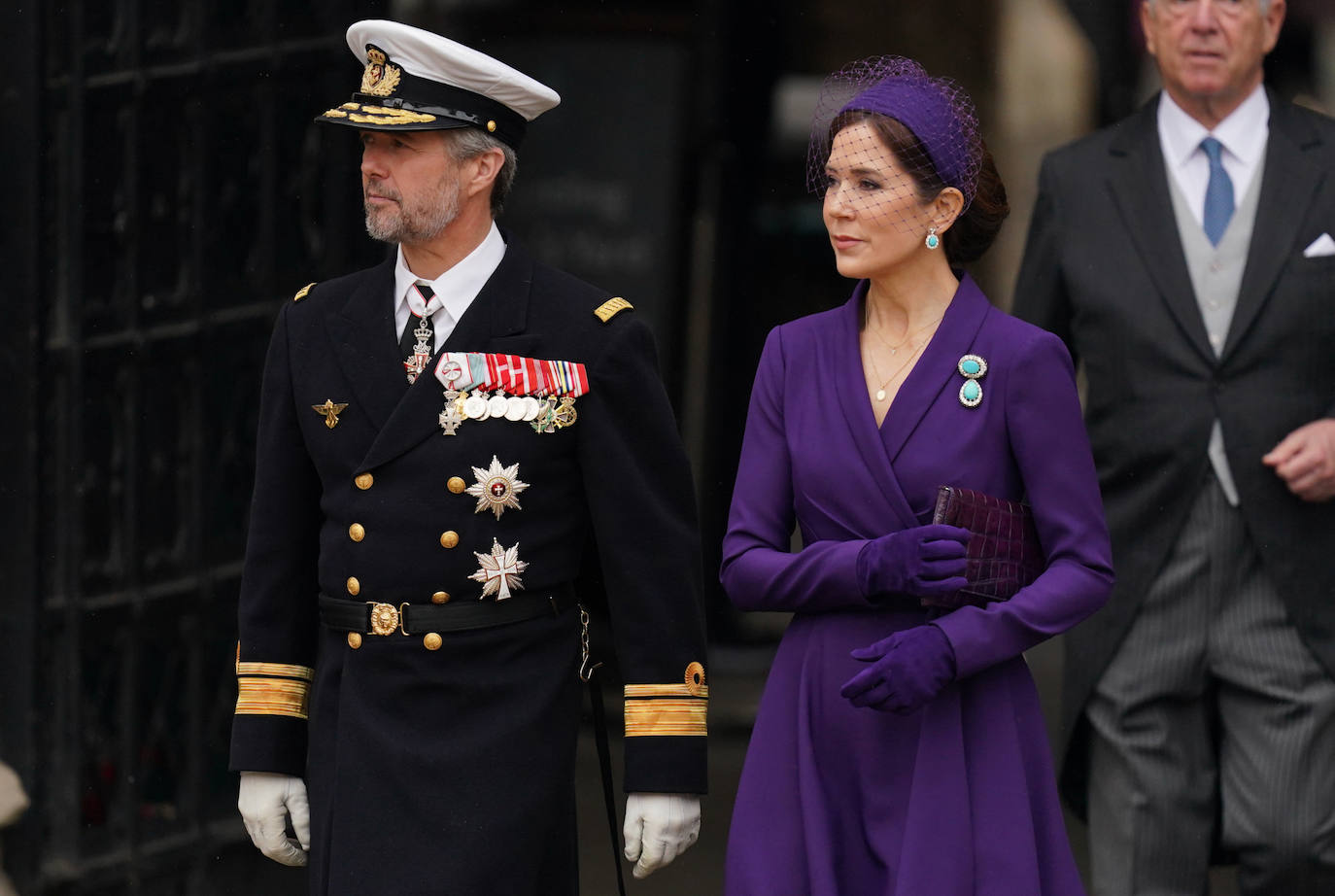 Federico de Dinamarca y Mery, que ha elegido un bonito estilismo en color morado,formado por un vestido cruzado, tocado con rejilla y guantes. 