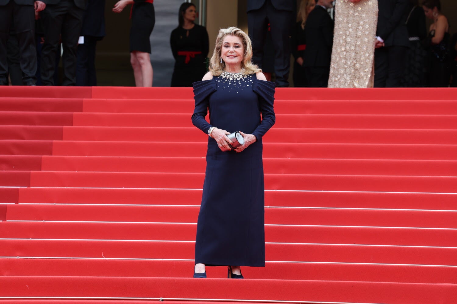 Catherine Deneuve llevó un vestido hecho a medida azul marino con detalle de manga drapeada y bordado de cristal en el escote de Louis Vuitton.