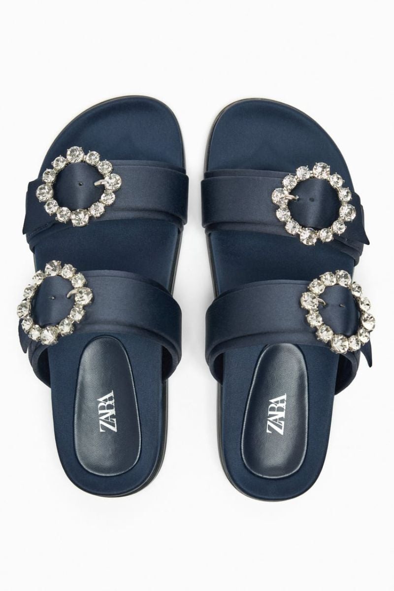 Zara. Sandalias de tipo Birkenstock con gruesas tiras y acabado satinado que incluyen unas flores con pedrería en los laterales que les dan un acabado todavía más chic. Precio: 39,95€.