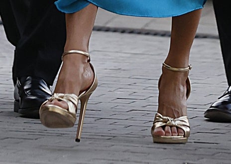 Imagen secundaria 1 - La Reina ha combinado su conjunto con complementos dorados: pendientes largos, sandalias de tacón alto de Jimmy Choo y bolso de Magrit. 